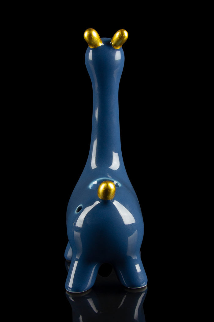 Blue glass water pipe shaped like a giraffe with gold accents, reflecting on a black surface.