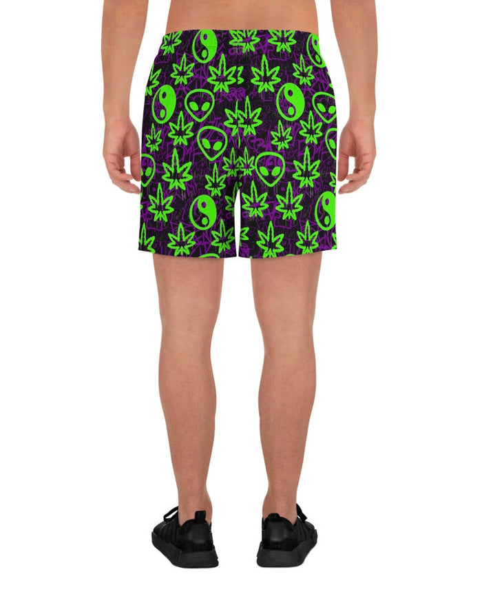 Shorts with green alien and marijuana leaf designs on a model with white background