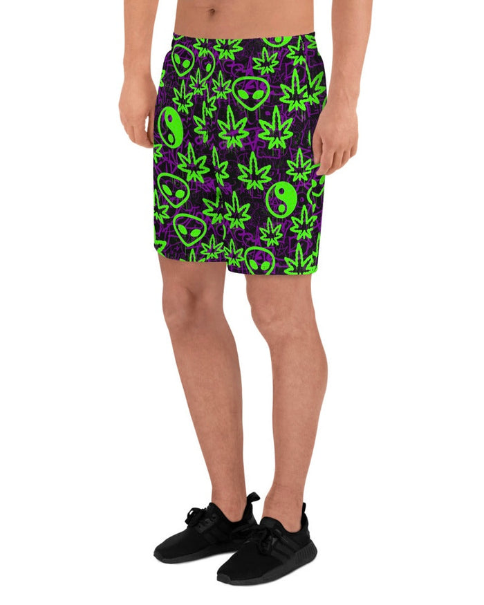 Shorts with green alien and marijuana leaf designs on a model with white background