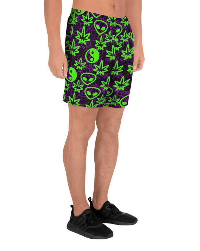 Shorts with green alien and marijuana leaf designs on a model with white background