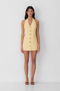 Best-selling women’s Butter Yellow Irida mini halter neck vest dress with gold swirl buttons, tie-back, and front welt pocket—wear alone or with matching pants.
