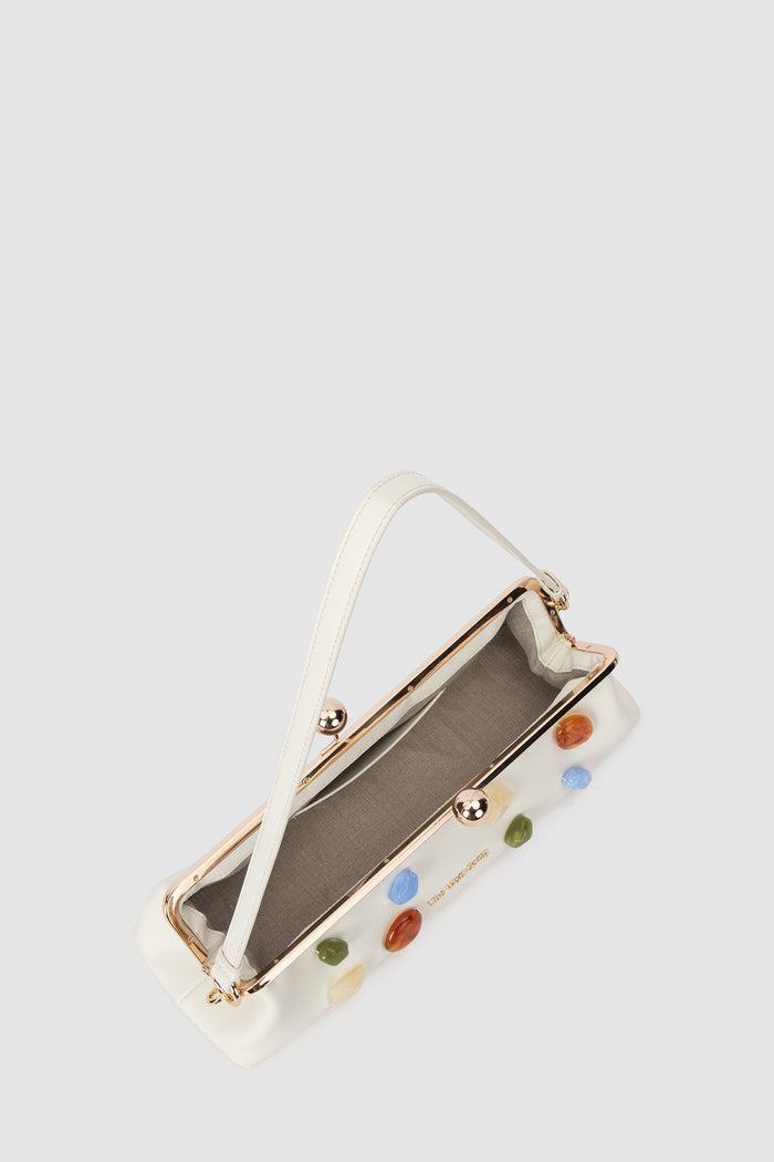Inside of handbag with colourful gemstone embellishments on a light grey background