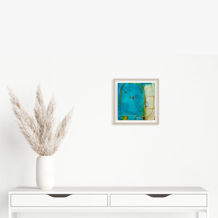 The artwork 'LS no. 20' by Janice La Motta features vibrant turquoise blue abstract forms blending with subtle yellow accents, creating a dynamic composition on Yupo paper. The oil pastel technique creates rich, textural elements against the smooth surface, displayed in a minimalist white frame. Original artwork measures 9x9 inches by Janice La Motta.