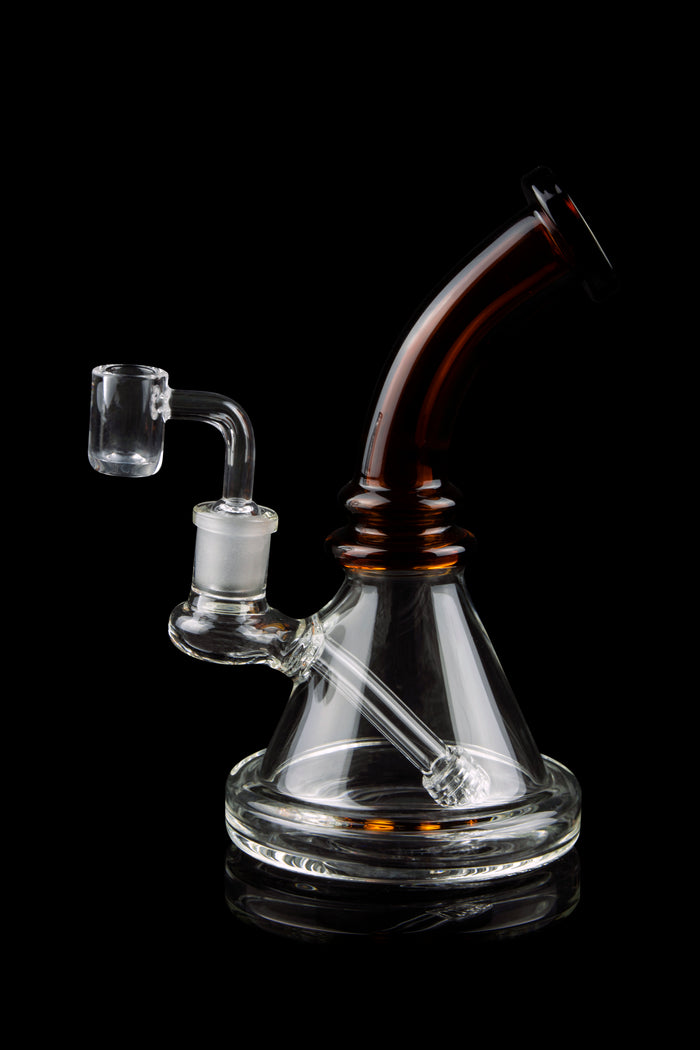 Clear glass dab rig with a quartz banger, isolated on a black background.
