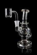 Clear glass dab rig with a quartz banger, isolated on a black background.
