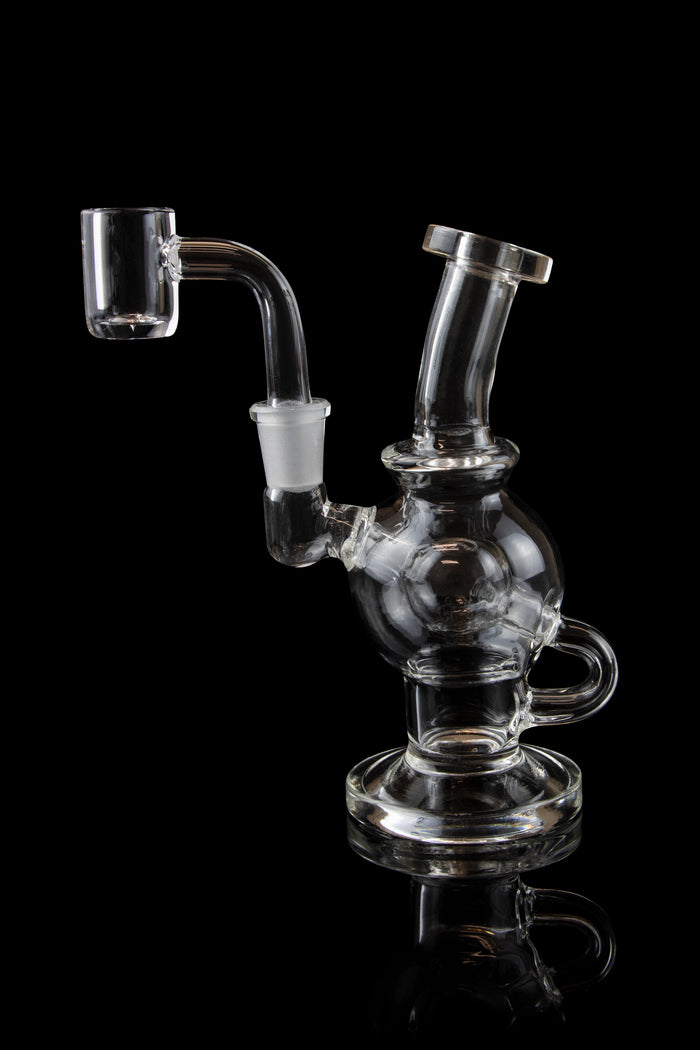Clear glass dab rig with intricate bubbler design, isolated on a black background.