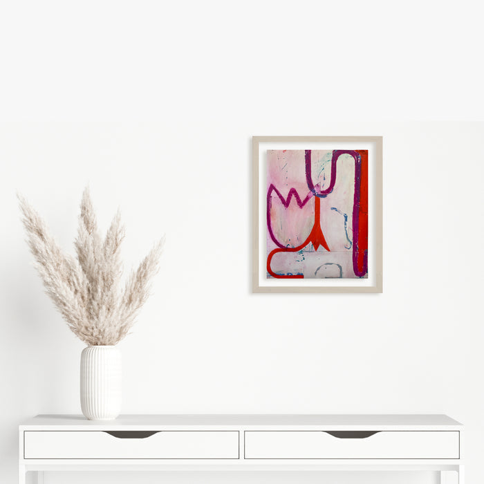 Spring Fling 6 by Janice La Motta: Abstract oil pastel artwork featuring fluid organic shapes in pink, red, and blue tones against a light background. Bold curved lines create a playful, dynamic composition on Yupo paper, with gestural marks suggesting natural forms and movement. Framed in white, displayed above modern white furniture.